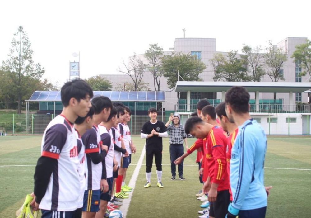 Young men gathered around a soccer field in South Korea.