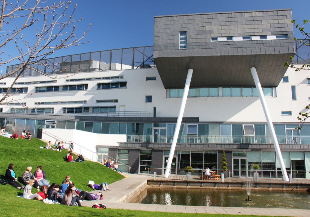 People sitting on the grass near a building.