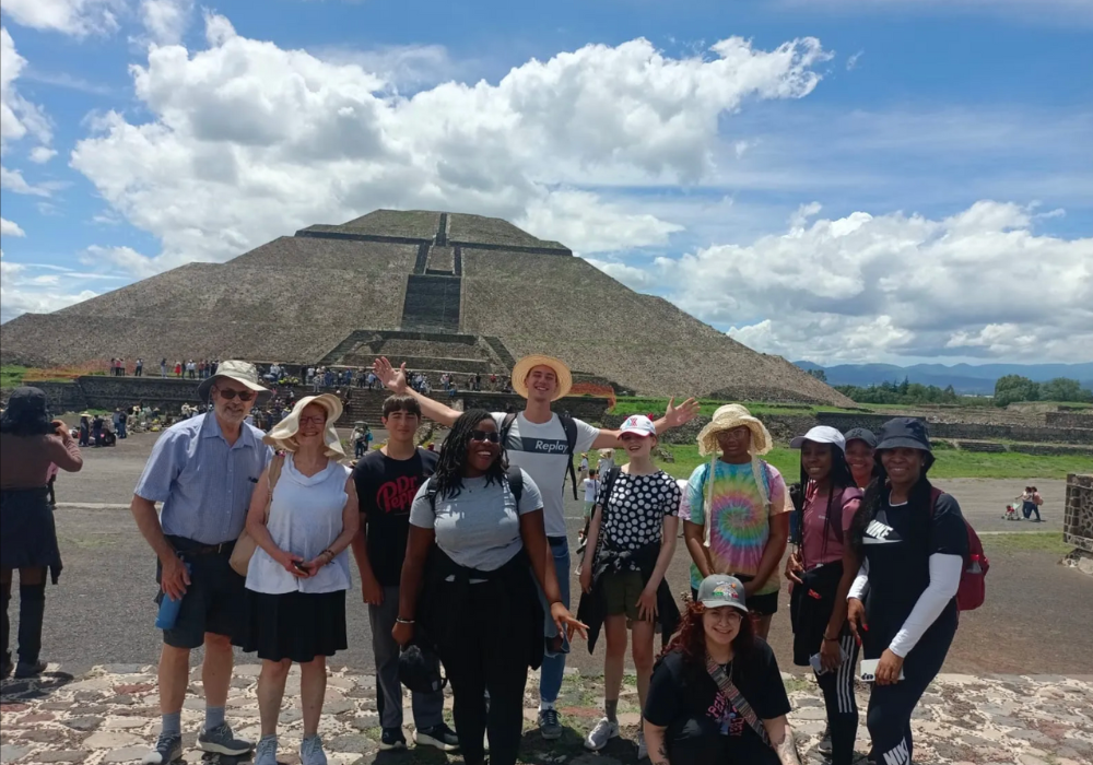 A group of people smiling and posing for a photo in front of a pyramid in Mexico.