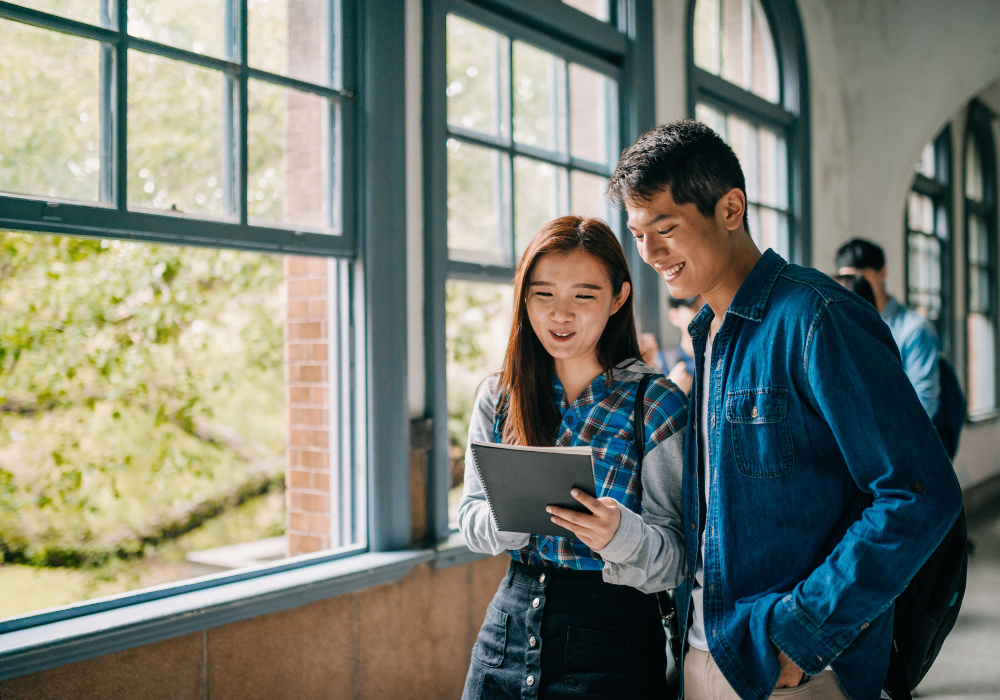 Two students standing together in a school corridor.