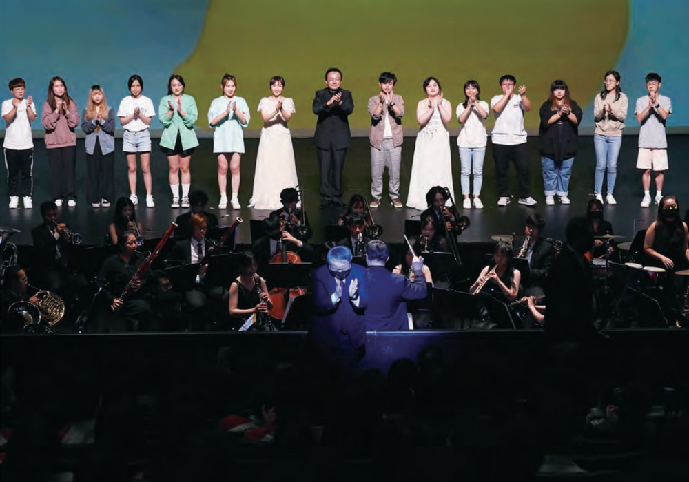 A group of musicians on stage with a conductor leading them.